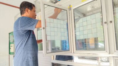 Abd. Rahman Baderan saat mengisi ulang air minum di depotnya, Minggu (14/6/2026). (Foto: Isam/Diskominfotik).
